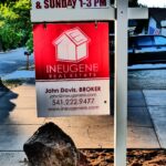 A home for sale sign with an open house rider on a front lawn